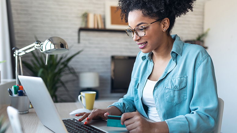 a woman wearing glasses while smiling and looking at a computer