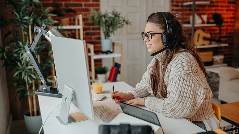 woman wearing headphones and looking at a desktop